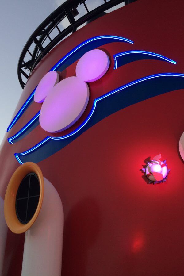 Disney Cruise Line logo on the Disney Fantasy steam stack at dawn.