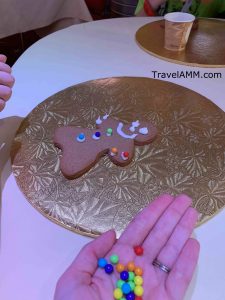 Child putting colorful decorations on iced gingerbread cookie during a very merrytime cruise on the disney cruise line
