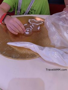 iced gingerbread cookie with child putting decorations on it