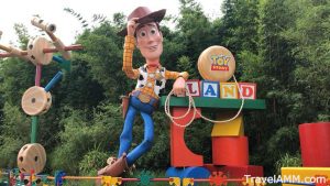 Woody standing next to some building blocks and a yoyo that spell out Toy Story Land