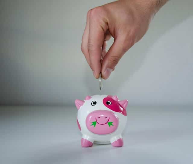 Man saving money in a pink piggy bank
