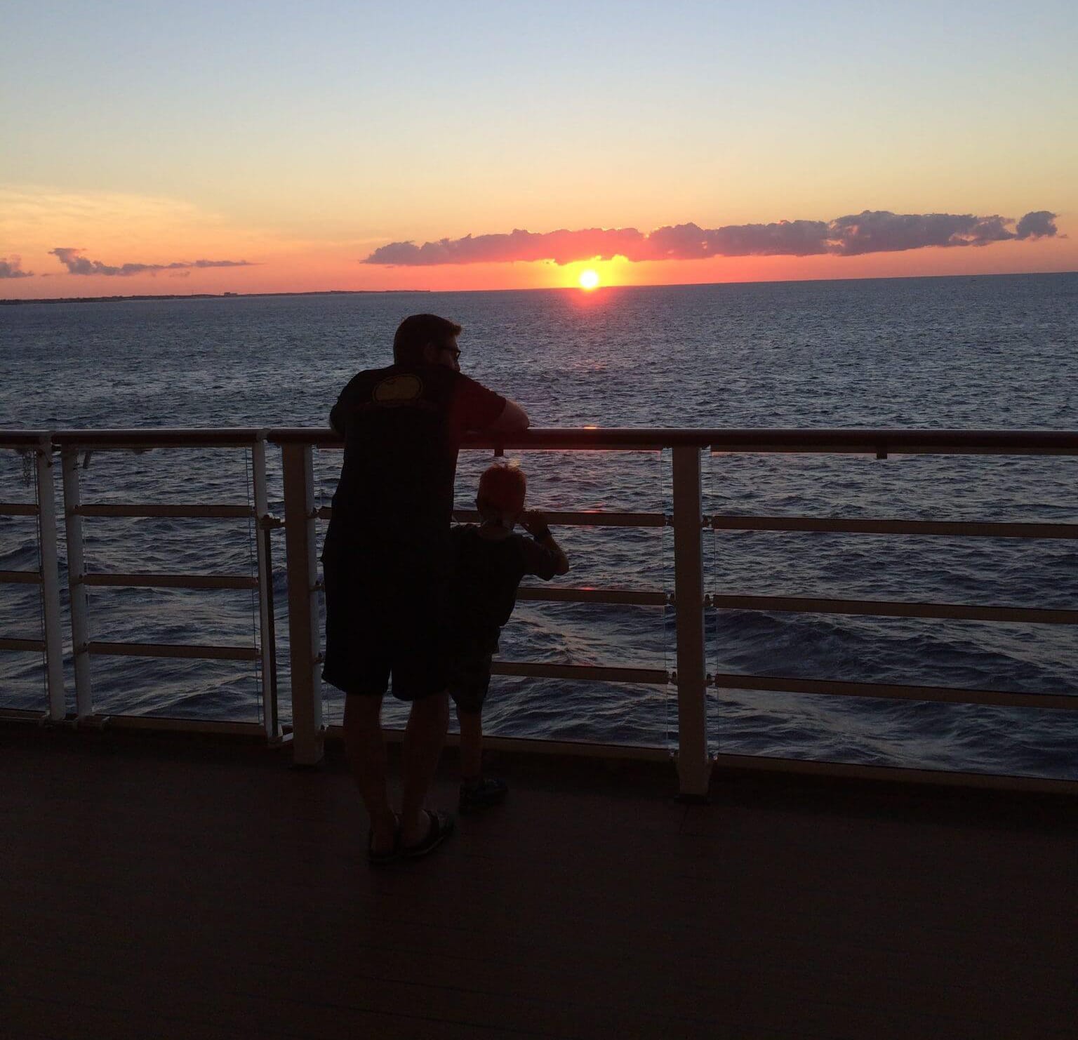 man and boy in silhouette standing on a pier at sunset