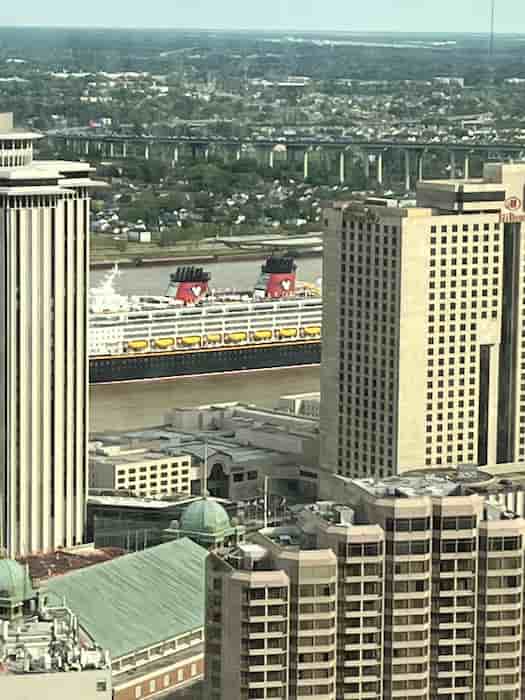 Zoomed in picture of the Disney Magic between tall buildings along the Mississippi River in March 2023