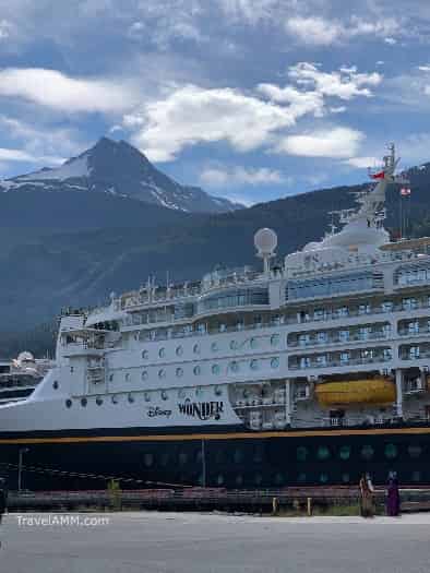 Disney Wonder in Port in Juneau Alaska with mountains and blue sky in the background